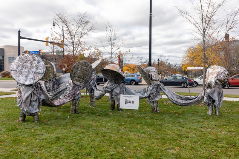 Students dressed as a connecting silver statue